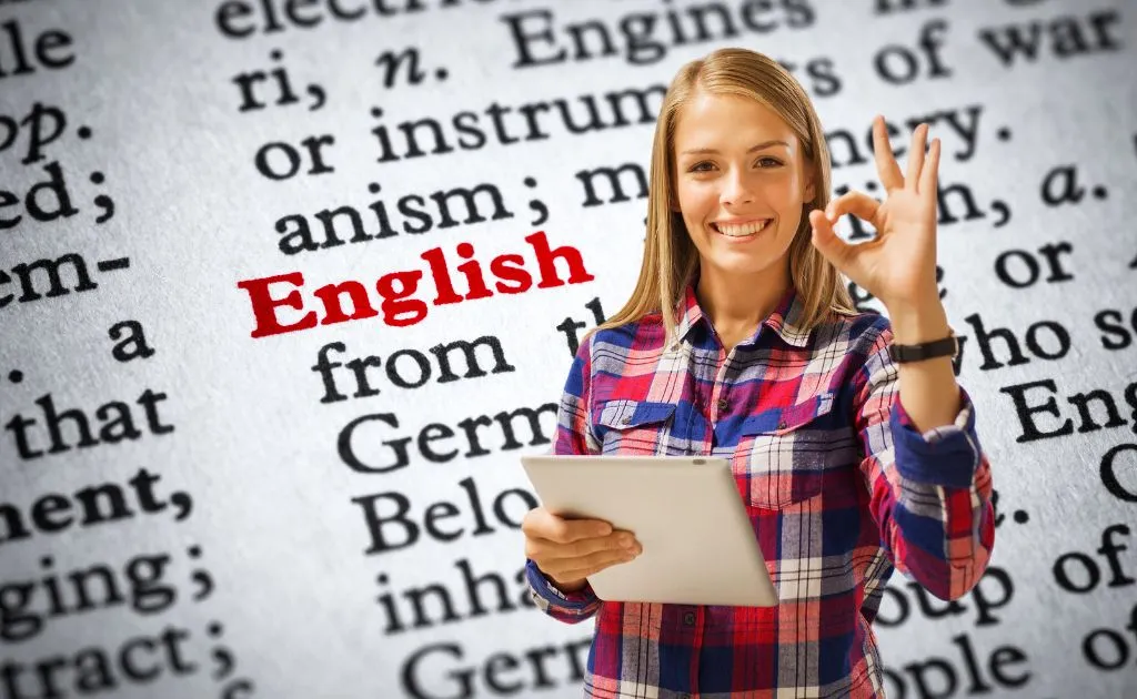 Ragazza sorridente con tablet che fa il segno ok davanti a un dizionario di inglese, soddisfatta della sua esperienza di apprendimento online